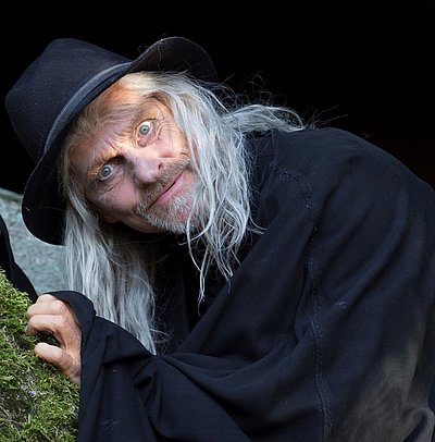 Luisenburg Festspiele im Fichtelgebirge - Mann mit grauen Haaren im schwarzen Hexerkostüm schaut in die Kamera
