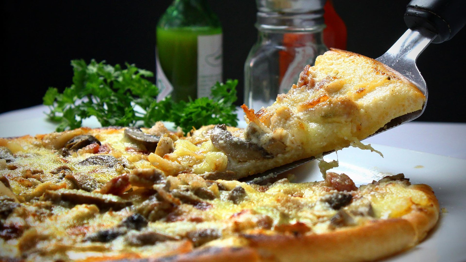 Partyservice und Lieferservice in Oberbayern - Person nimmt ein Viertel von einer frischen Pizza
