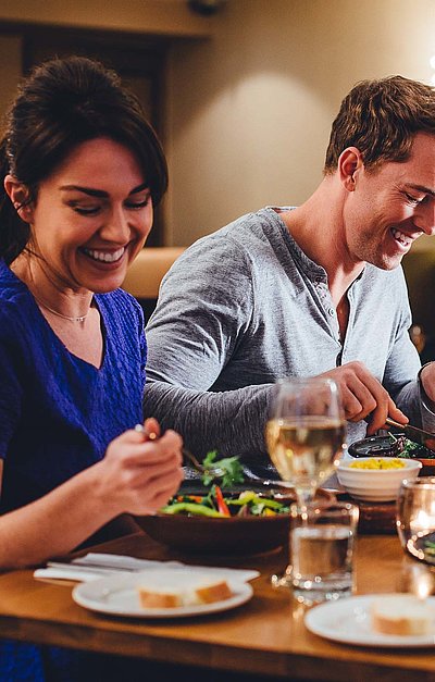 Gastronomie für Gruppen im Ostallgäu - eine Gruppe von Gästen lacht zusammen an einem bedeckten Tisch