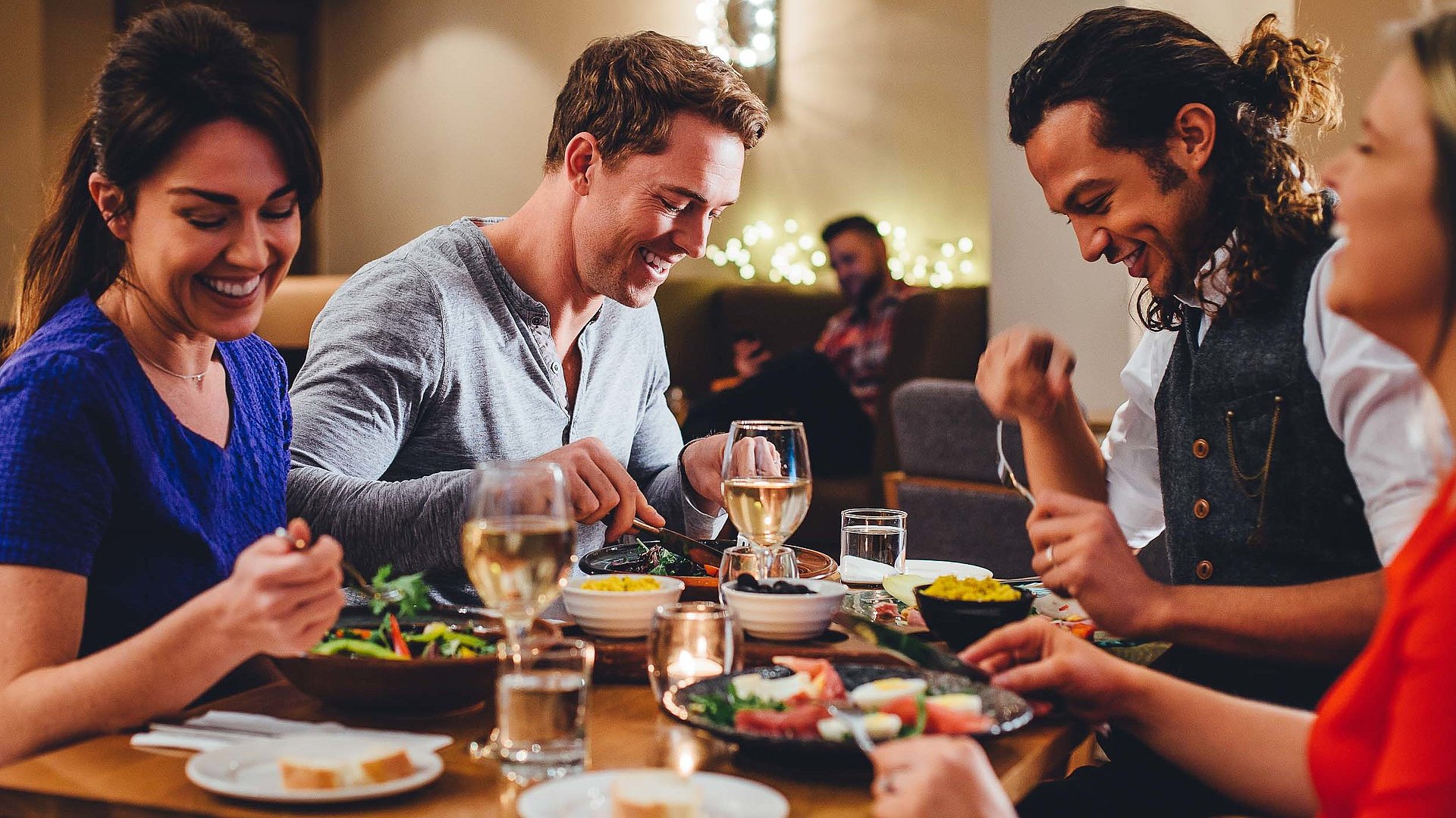 Gastronomie Für Gruppen in Oberbayern - eine Gruppe von Gästen lacht zusammen an einem bedeckten Tisch