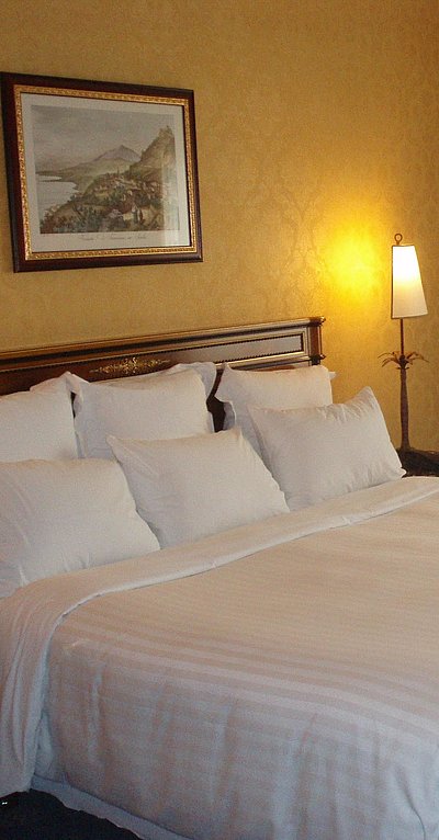 Pauschalen für die Wochentage in Kempten - sehr ordentliches Hotelzimmer mit großem Bett, warmer Nachtlampe und mittelgroßem Wandgemälde