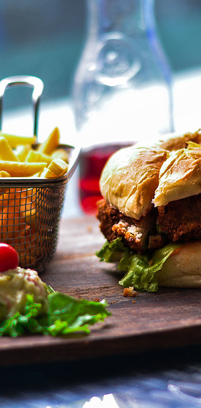 Gastronomie im Video in Unterfranken - im Restaurant; Burger, Pommes und Salat auf einem Holzbrett