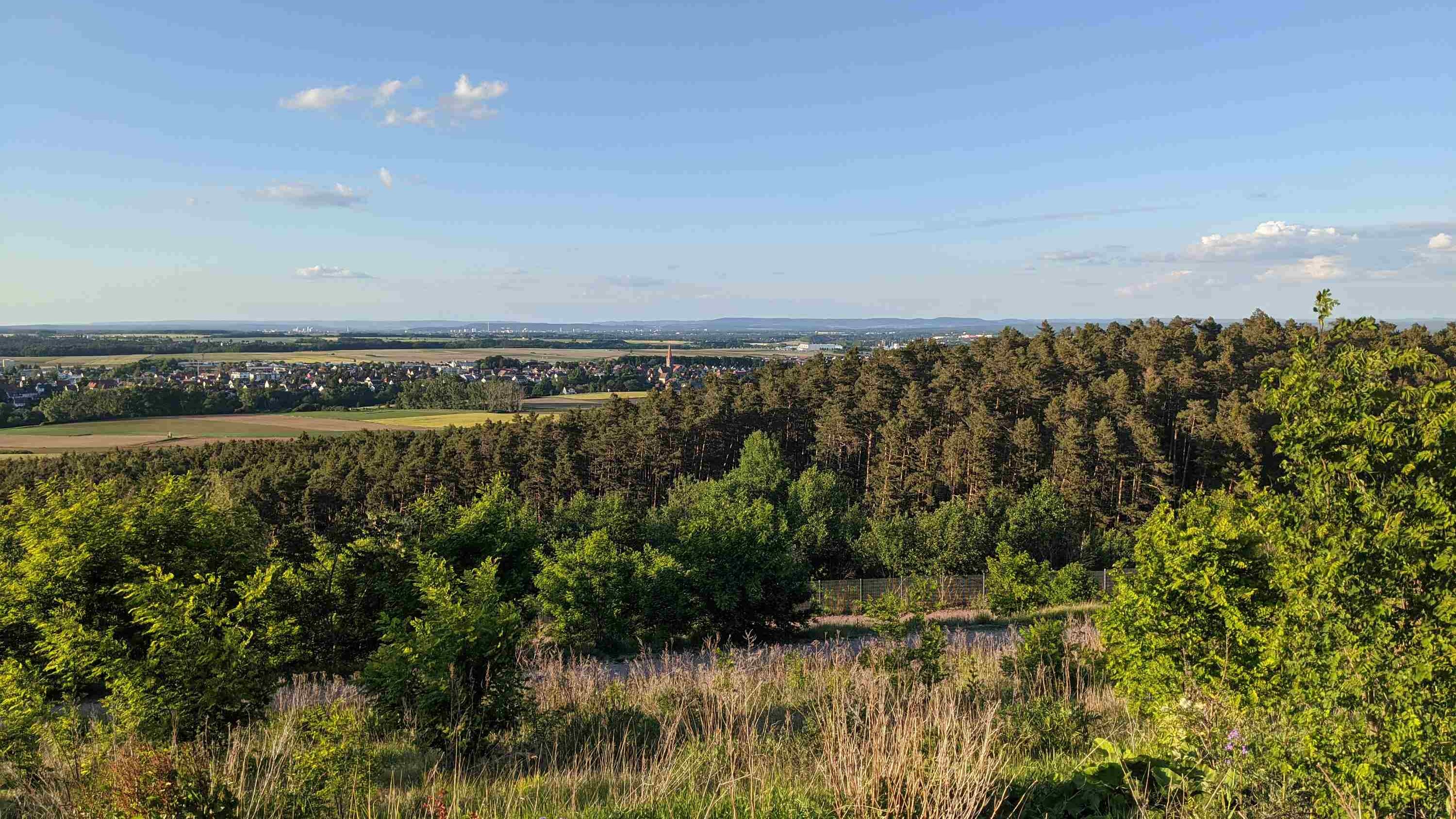 Blick vom Aussichtspunkt Cadolzburg-Seukendorf. Baeume im Vordergrund weiter unten Burgfarrnbach