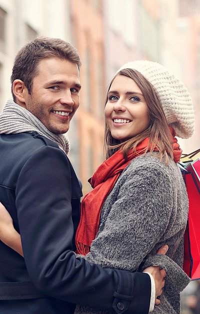Einkaufen in Unterfranken - junges Paar mit Einkaufstüten lächelt in die Kamera