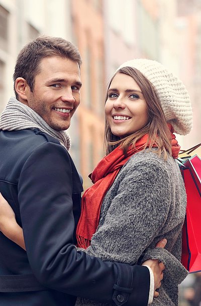 Exklusiv Einkaufen in Oberbayern - junges Paar mit Einkaufstüten lächelt in die Kamera