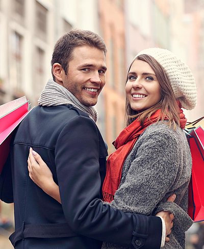 Einkaufen im Oberallgäu - junges Paar mit Einkaufstüten lächelt in die Kamera