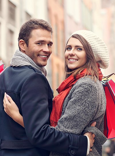 Einkaufen in Franken - junges Paar mit Einkaufstüten lächelt in die Kamera
