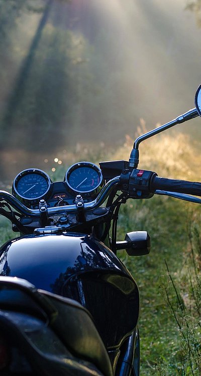 Motorrad-Urlaub im Oberallgäu - schwarzes Motorrad steht in einer Waldlichtung