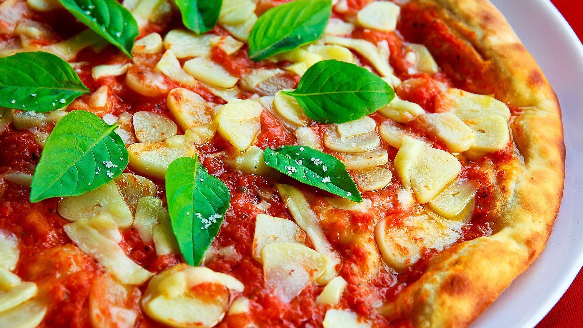 Italienische Küche im Oberallgäu - frische Pizza mit saftiger Tomatensoße und Pilzen, bestückt mit Basilikum 
