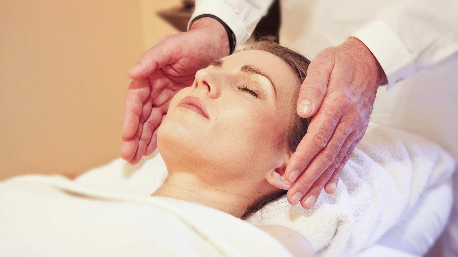 Wellness in Franken - junge Frau auf einem Massagebett genießt Kopf-Massage
