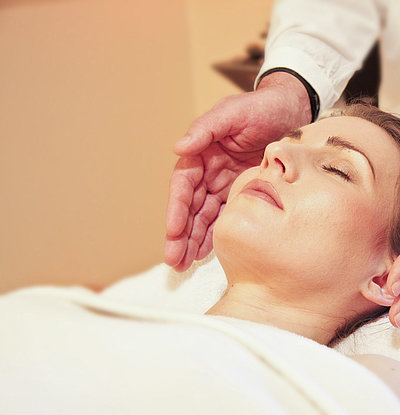 Wellness in Franken - junge Frau auf Massagebett genießt Kopf-Massage
