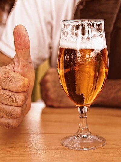 Biergarten in Mittelfranken - fast volles Bier auf Holztisch; Mann im Hintergrund zeigt Daumen Hoch