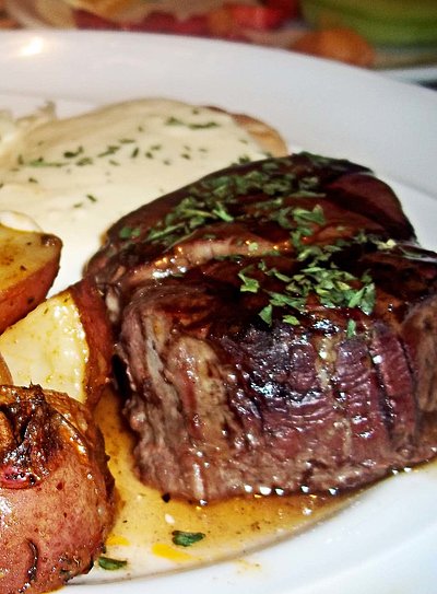 Steaks Essen in Kempten im Allgäu - Teller gefüllt mit frischem Rinder-Steak, Kräuterbutter, gebratenen Kartoffeln und Salat