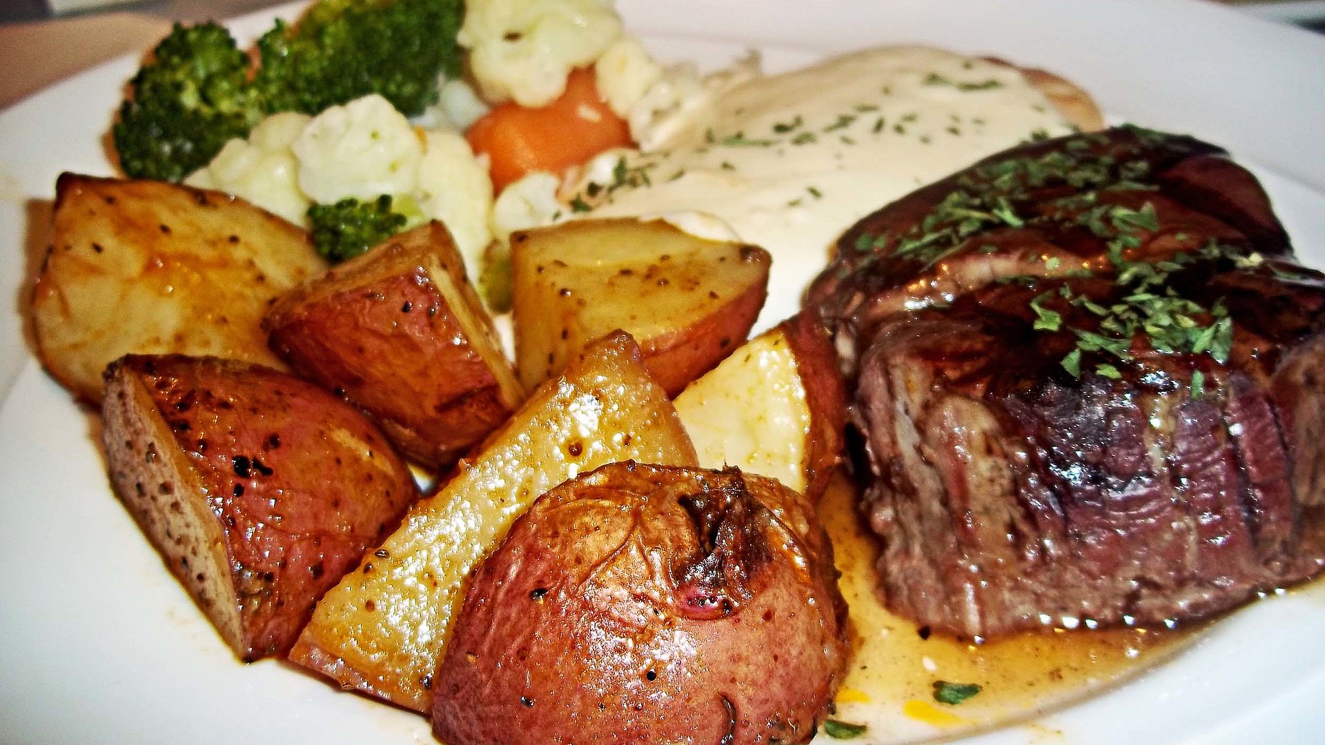 Steak Essen in Nürnberg - Tisch gefüllt mit u.a. Steak und gebratenen Kartoffeln