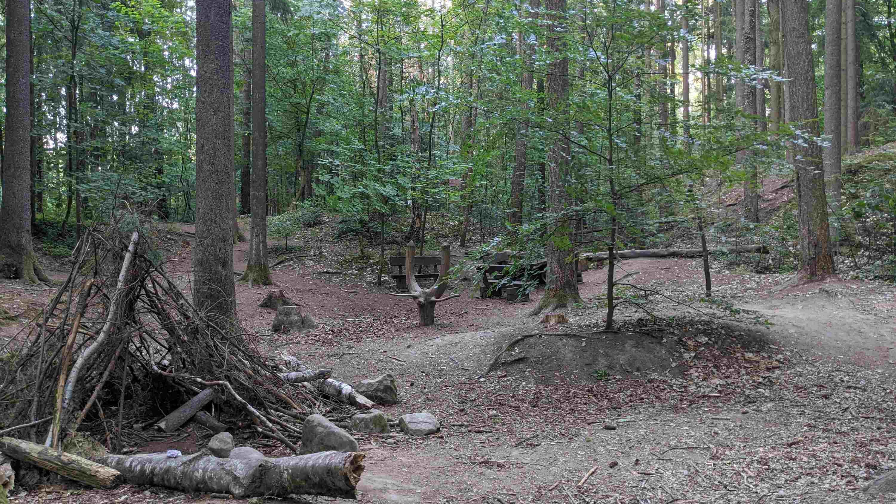 Naturspielplatz des Naturlehrpfades im Stadtwald Fuerth. Provisorischer Unterstand aus Aesten und Sitzgelegenheit aus Wurzel.