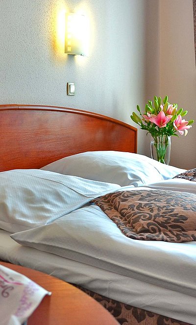 Übernachten im Panorama Oberfranken - im Hotelzimmer, gemachtes Zimmer mit Blumen am Nachttisch 