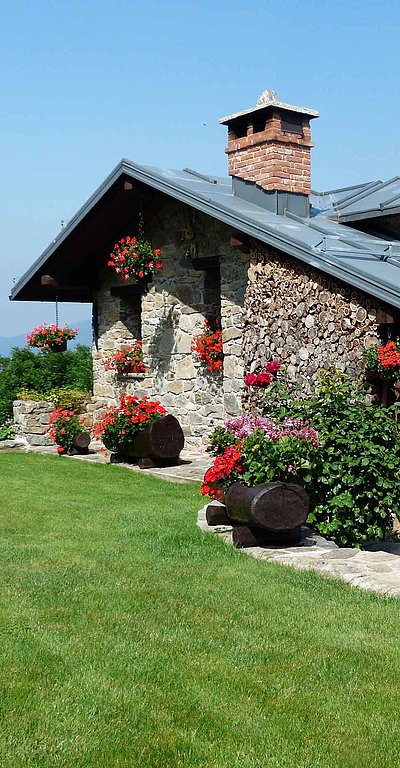Ferienwohnungen und Ferienhäuser für Gruppen im Oberallgäu - großes Ferienhaus mit ordentlichem Garten und Hügellandschaft im Hintergrund 