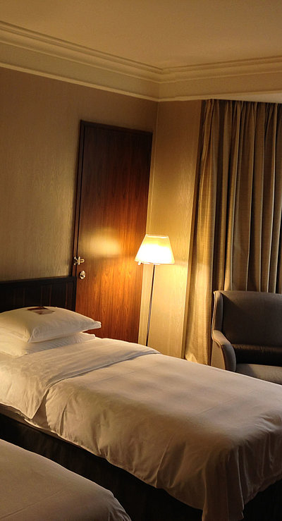 Pauschalen für eine Woche in Franken - sehr ordentliches Hotelzimmer mit zwei Betten, warmer Nachtlampe und Gardinen