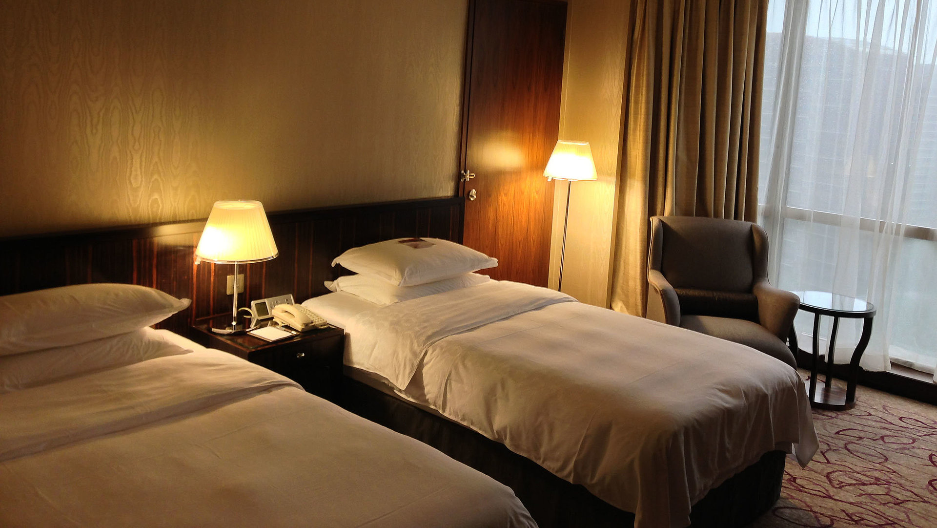 Pauschalangebote für Unterkunft im Oberallgäu - sehr ordentliches Hotelzimmer mit zwei Betten neben beleuchteten Nachtlampen; Zimmer mit weißer Gardine