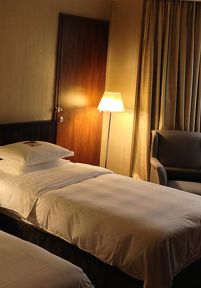 Hotels für Gruppen in Oberbayern - sehr ordentliches Hotelzimmer mit zwei Betten, warmer Nachtlampe und Gardinen