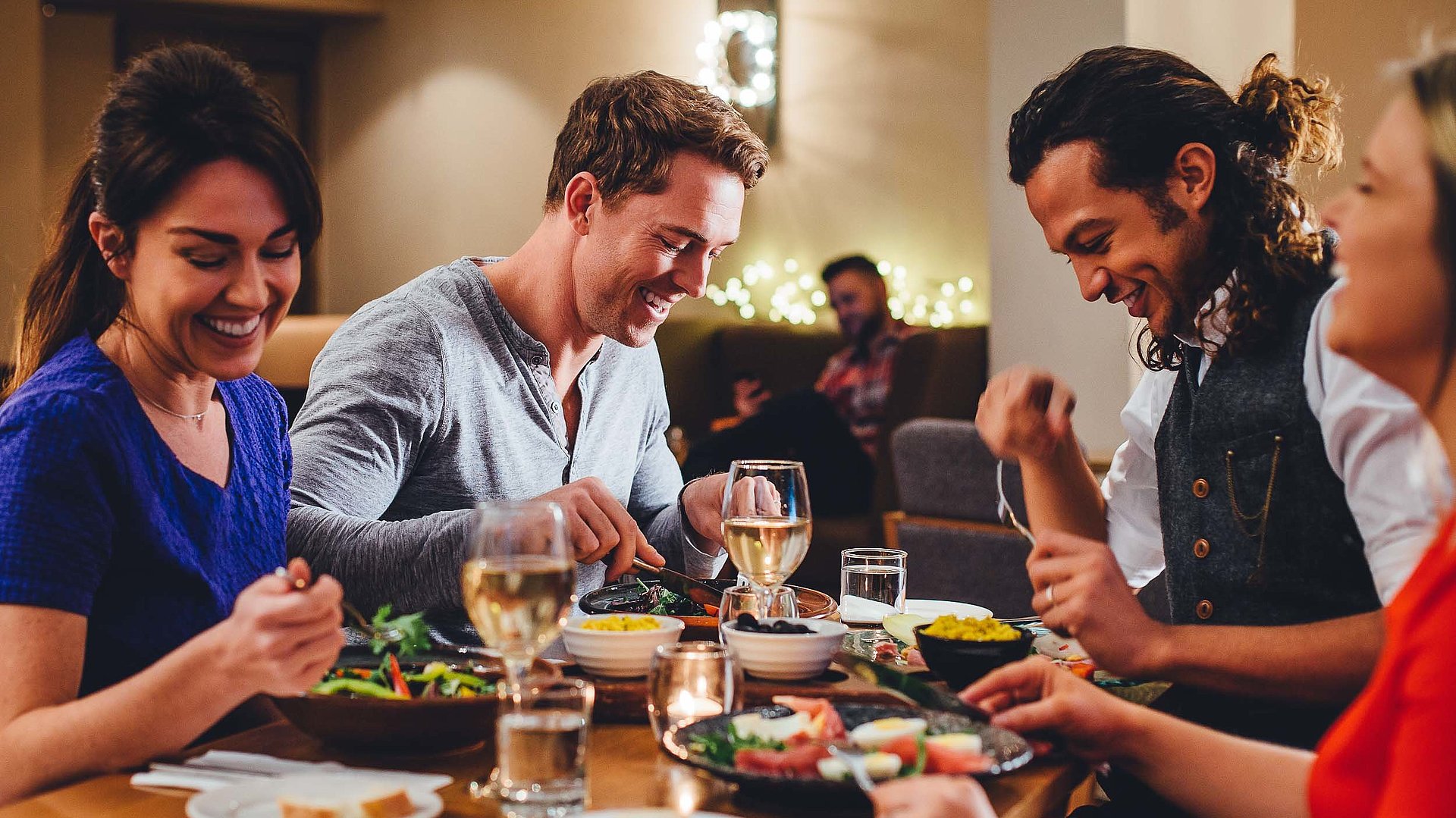 Gastronomie für Gruppen im Oberallgäu - eine Gruppe von Gästen lacht zusammen an einem bedeckten Tisch