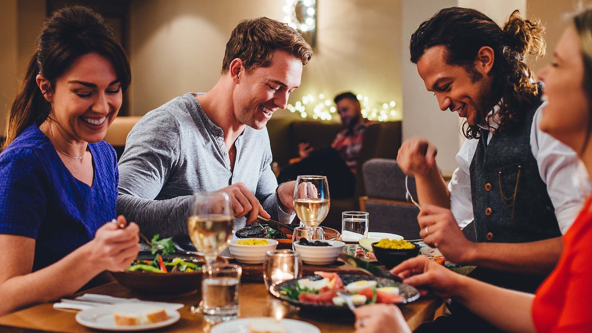 Abendessen in Franken - eine Gruppe von Gästen lacht zusammen an einem bedeckten Tisch