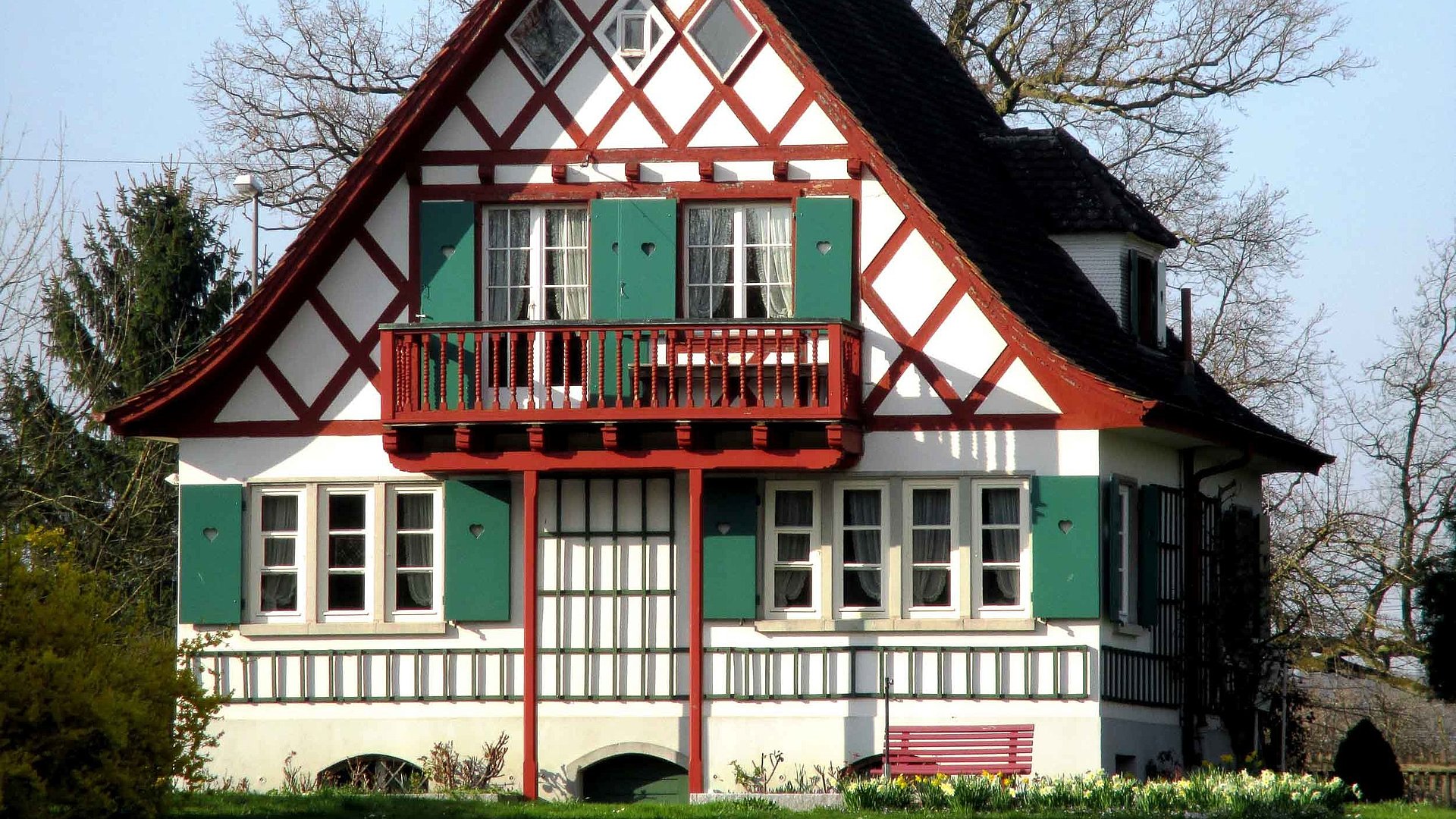 Exklusive Ferienwohnungen im Fichtelgebirge - Bayerisches Haus mit Balkon unter klarem Himmel, grünem Garten und Bäumen im Hintergrund