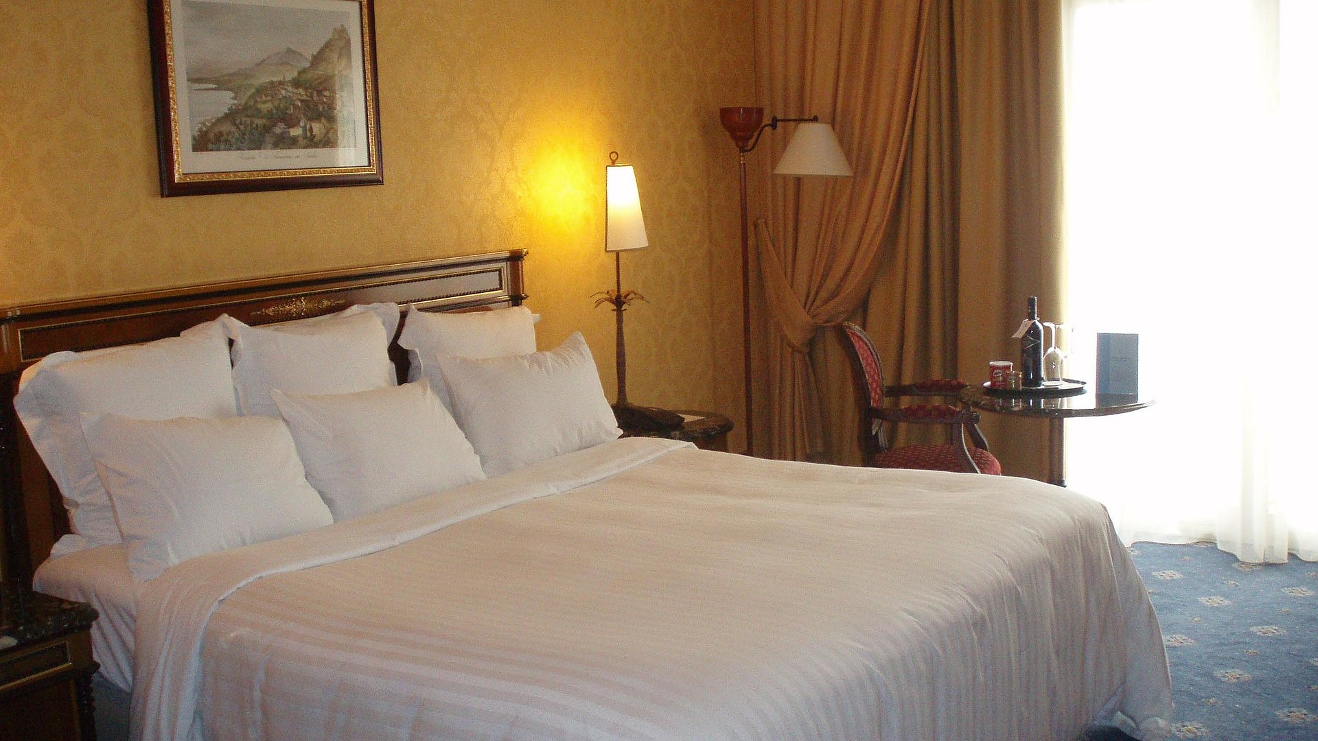 Hotel garni in Nürnberg - sehr ordentliches Hotelzimmer mit großem Bett und warmer Nachtlampe wird durch weiße Gardinen durchleuchtet