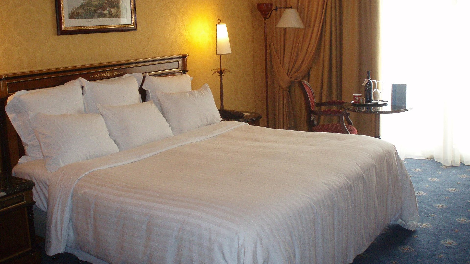 Hotels für Gruppen in Franken - sehr ordentliches Hotelzimmer mit großem Bett, warmer Nachtlampe und mittelgroßem Wandgemälde