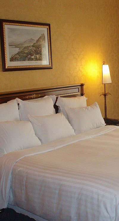 Hotels für Gruppen in Kempten - sehr ordentliches Hotelzimmer mit großem Bett, warmer Nachtlampe und mittelgroßem Wandgemälde