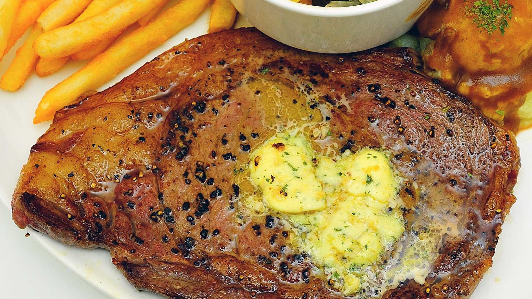 Steak Essen in Kempten im Allgäu - Teller gefüllt mit frischem Rinder-Steak, Kräuterbutter, gebratenen Kartoffeln und Salat
