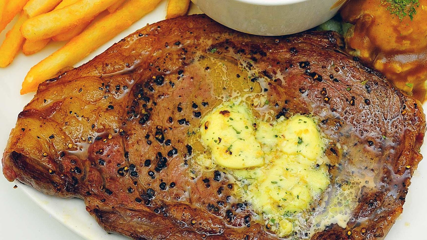 Steak Essen in Oberfranken - Teller gefüllt mit frischem Rinder-Steak, Kräuterbutter, gebratenen Kartoffeln und Salat
