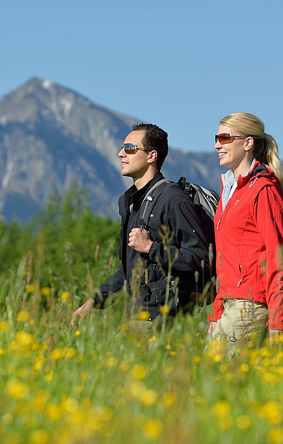 Wandern und Wanderurlaub in Unterfranken - zwei Partner auf Wanderung in Graslandschaft; Berge im Hintergrund