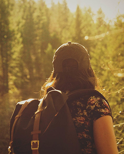 Wanderfreundliche Unterkünfte im Fichtelgebirge - Frau mit Rucksack und Rücken zur Kamera steht im Wald