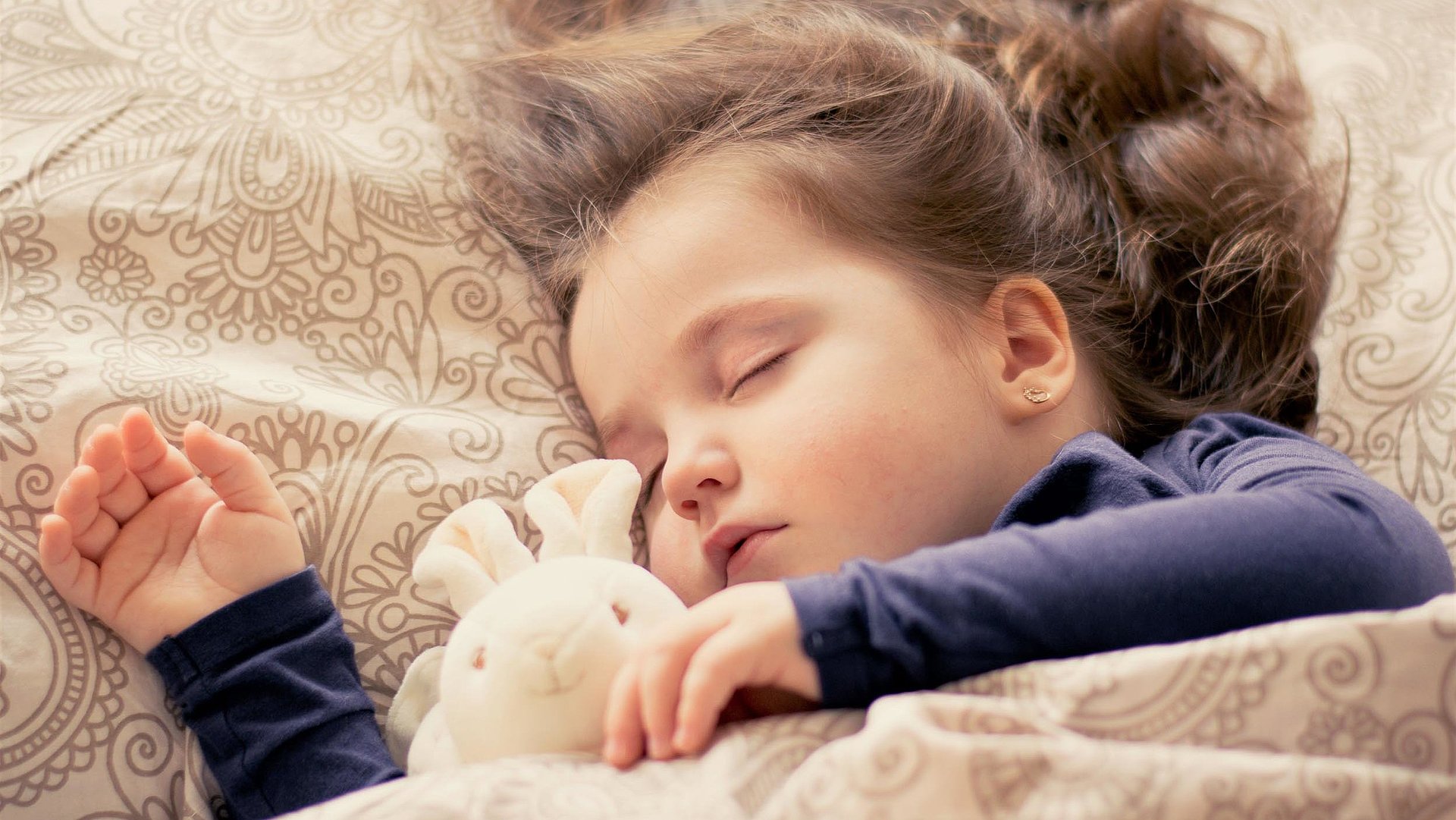 Kinderfreundliche Unterkünfte in Franken - kleines Mädchen mit Plüschtierhäschen liegt schlafend im Bett