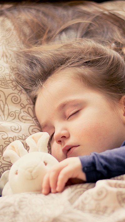 Kinderfreundliche Unterkünfte in Franken - kleines Mädchen mit Plüschtierhäschen liegt schlafend im Bett