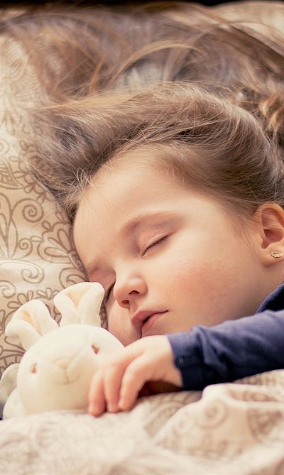Kinderfreundliche Unterkünfte in Mittelfranken - kleines Mädchen mit Plüschtierhäschen liegt schlafend im Bett