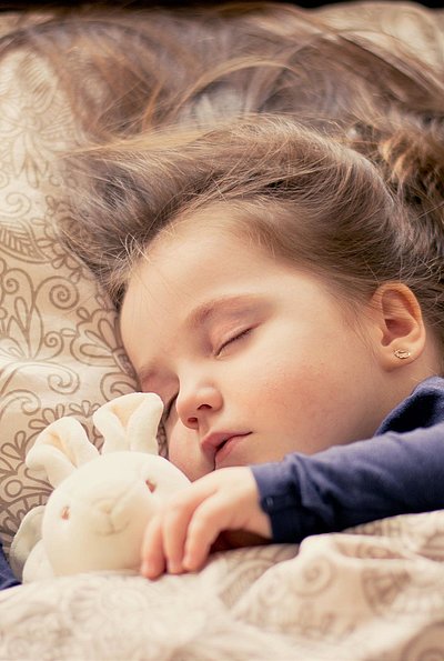 Kinderfreundliche Angebote im Fichtelgebirge - kleines Mädchen mit Plüschhäschen liegt schlafend im Bett
