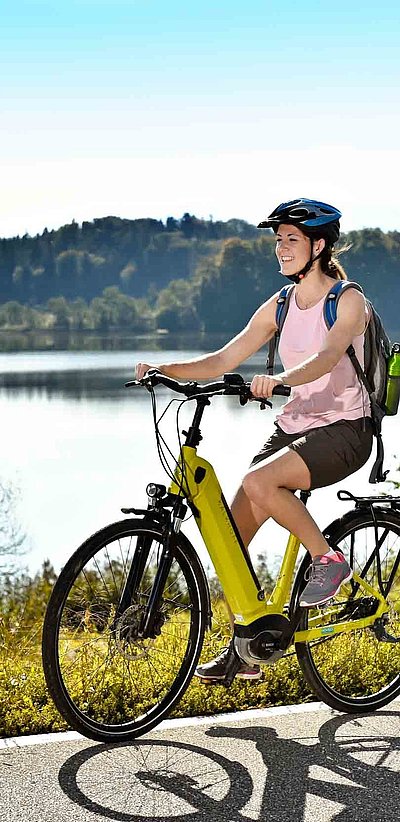 Incentives in Unterfranken - zwei Partner auf E-Bike fahren am See entlang; Waldgebiet im Hintergrund