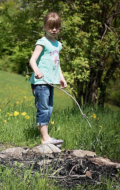 Kinderfreundliche Gastronomie im Fichtelgebirge - junges Mädchen spielt auf der Wiese mit einem dünnen Stock