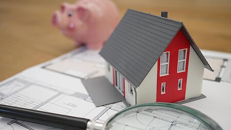 Wie finden Bauherren einen günstigen Baukredit? - Modellhaus auf einem Plan