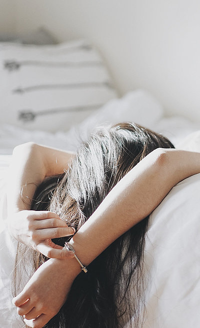 Pauschalen für eine Woche in Unterfranken - junge Frau liegt mit dem Rücken auf dem Bett und schaut zur Decke
