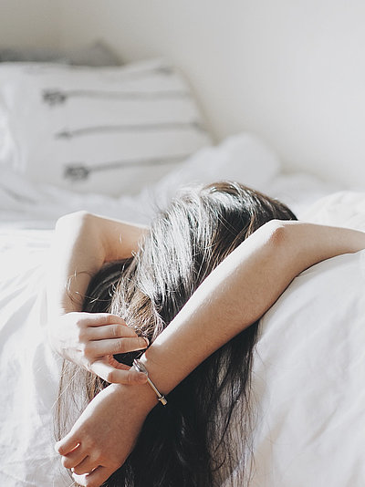 Pauschalen für das Wochenende im Fichtelgebirge - junge Frau liegt mit dem Rücken auf dem Bett und schaut zur Decke