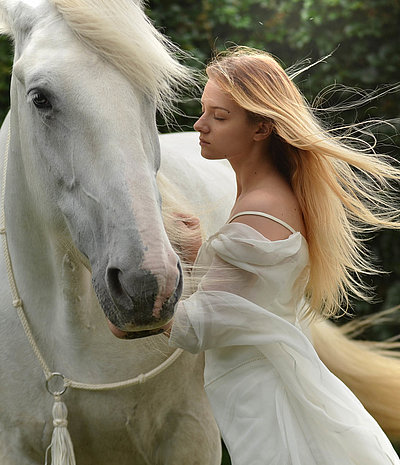 Reiten und Reiturlaub im Fichtelgebirge - junge Frau mit langem blonden Haar und weißem Kleid streichelt weißes Pferd 
