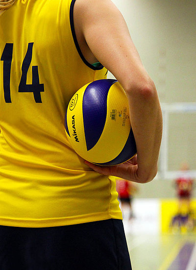 Freizeit und Sport in Oberbayern - Frau mit Volleyball im Arm in einer Sporthalle