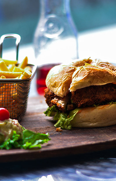 Gastronomie im Panorama in Franken - Burger, Pommes und Salat auf einem Holzbrett; im Restaurant