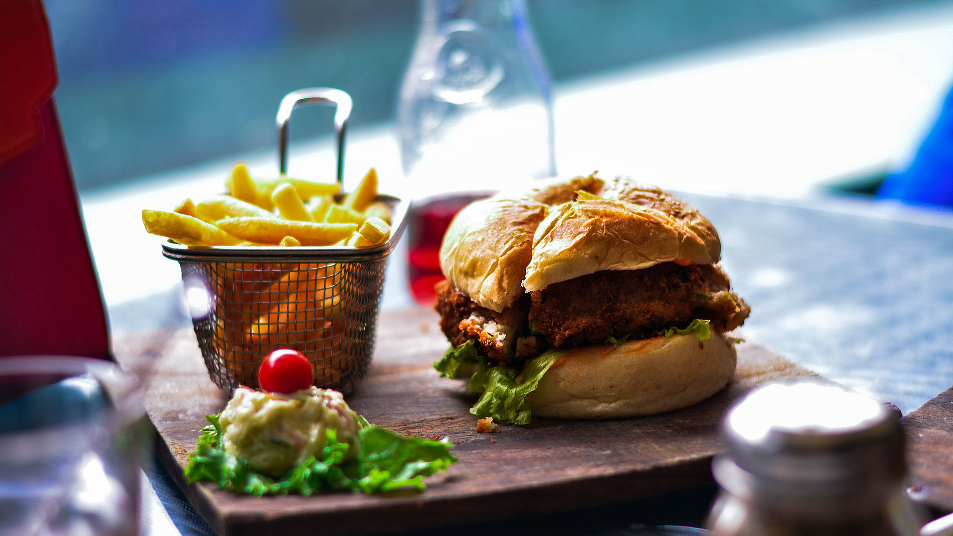 Gastronomie in Oberfranken - im Restaurant; Burger, Pommes und Salat auf einem Holzbrett