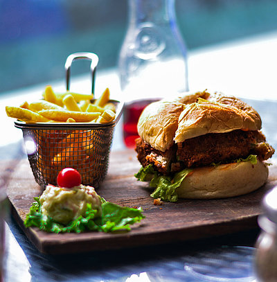 Cateringservice im Fichtelgebirge - im Restaurant; Burger, Pommes und Salat auf einem Holzbrett