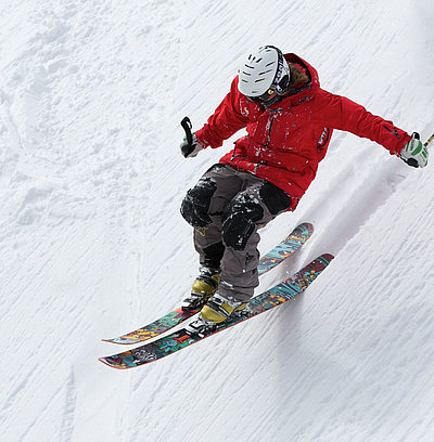 Wintersport-Unterkünfte im Fichtelgebirge - Mann in Skiausrüstung fährt soeben Schnee-Hügel runter