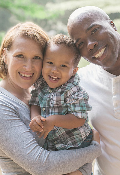 Kinderfreundliche Angebote in Mittelfranken - drei-köpfige Familie mit Kleinkind lächelt mit breitem Grinsen in die Kamera
